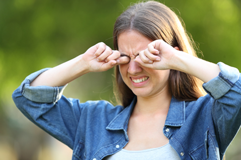 Woman suffering itching scratching eyes outdoors in a park